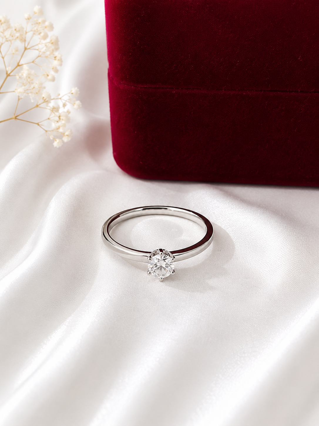 Elegant silver solitaire ring with a round-cut crystal stone displayed on soft white satin fabric.