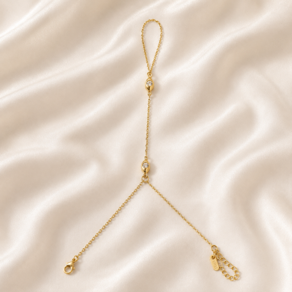 Minimal crystal gold hand chain bracelet on satin background