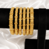 Luxury floral gold bangle set displayed on a black velvet stand
