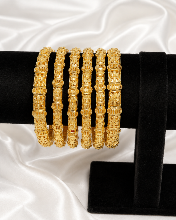 Luxury floral gold bangle set displayed on a black velvet stand