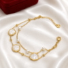 Elegant double-layer gold bracelet with pearl accents displayed on a white satin background