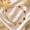 Luxury gold bracelet with multi-color crystal accents displayed on white satin background