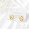 Gold daisy stainless steel ear studs on a white display card.