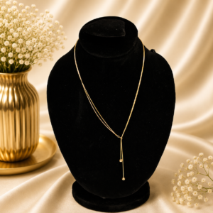 Minimalist gold stainless steel Y-drop necklace displayed on a black velvet jewelry stand.