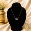 Gold stainless steel necklace with a crystal twin swan heart pendant displayed on a black velvet jewelry bust.