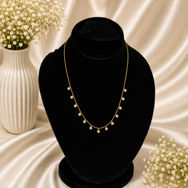Gold stainless steel necklace with multiple crystal drop charms displayed on a black velvet jewelry bust.