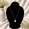 Gold stainless steel necklace featuring a round pearl-inspired pendant with a delicate rose design displayed on a black velvet jewelry bust.