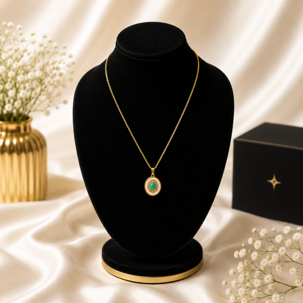 Gold stainless steel necklace with an emerald-inspired halo pendant displayed on a black velvet jewelry stand.