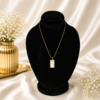 Gold stainless steel necklace with a white marble-style rectangle pendant displayed on a black velvet jewelry stand.