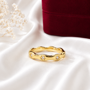 Gold stainless steel wave ring with sparkling crystal star accents displayed on a white satin background
