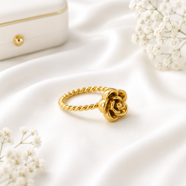 Gold stainless steel rose flower ring displayed on a white satin background.