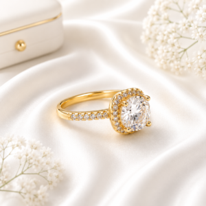 Gold stainless steel solitaire ring with a sparkling crystal centerpiece displayed on a white satin background
