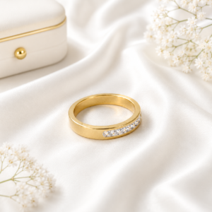 Gold stainless steel band ring with crystal accents displayed on a white satin background.