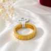 Gold stainless steel textured band ring displayed on a white satin background.